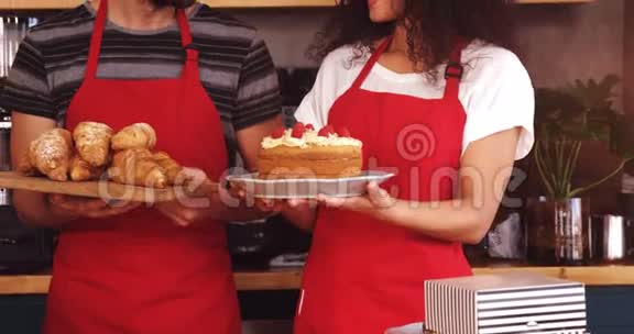 服务员拿着一盘羊角面包和蛋糕视频的预览图
