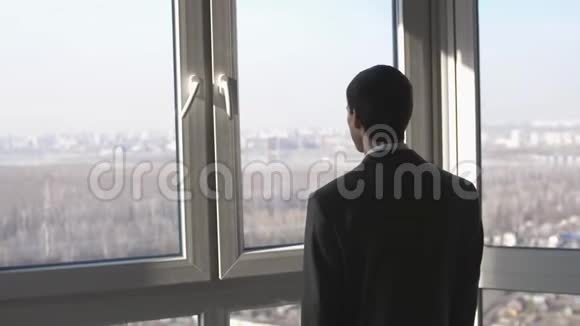 年轻的成功商人站在窗户前眺望城市的远方慢动作3840x2160视频的预览图