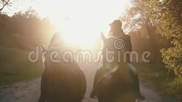 一对职业骑师在日落时骑马的特写镜头乡间小路在背景下被金色阳光照亮视频的预览图