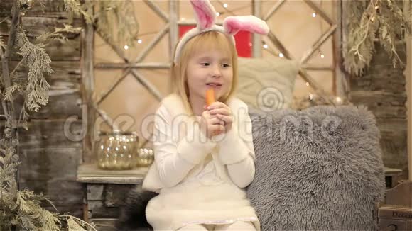 穿着兔子白色服装的小女孩坐在圣诞装饰中吃胡萝卜视频的预览图