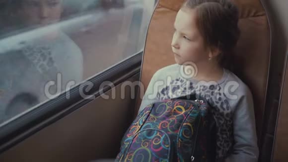 年轻美丽的女孩乘客拿着书包在移动的校车上看着窗外视频的预览图