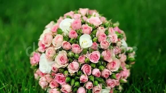 婚礼上的粉红色玫瑰花束躺在绿草上视频的预览图