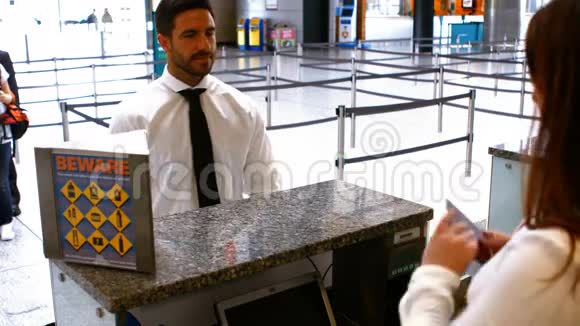 两名女机场工作人员在登记台检查护照并与通勤者互动视频的预览图