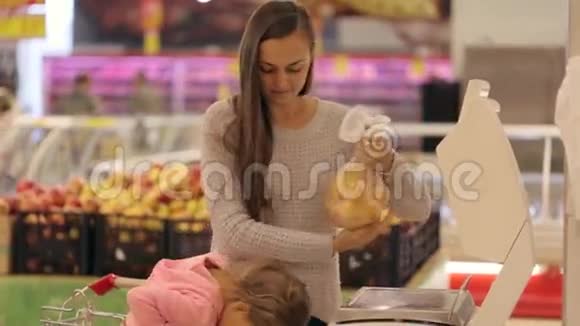 年轻的母亲在超市里她的蔬菜和水果重量很小视频的预览图