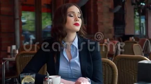 迷人的女商人穿着西装在户外咖啡厅用智能手机喝着咖啡慢动作专业的视频的预览图