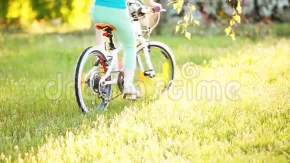 快乐的小女孩骑自行车在户外的绿草上在城市公园视频的预览图