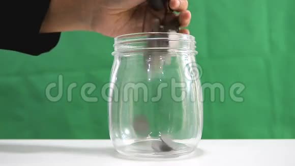 女人用手把硬币放到玻璃罐里赚钱和财务概念视频的预览图