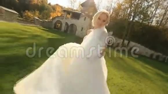 穿着白色裙子的迷人金发公主在中世纪城堡庭院的镜头前摆姿势视频的预览图