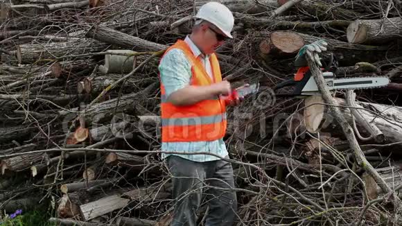 伐木工人在树枝堆上使用平板电脑视频的预览图
