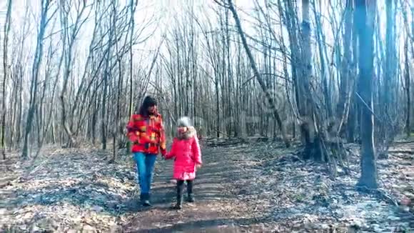 母亲和女儿正在阳光下穿过春天的森林视频的预览图