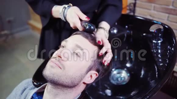 专业理发师给她英俊的客户洗头视频的预览图
