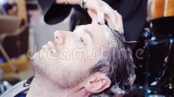 专业理发师给她英俊的客户洗头视频的预览图