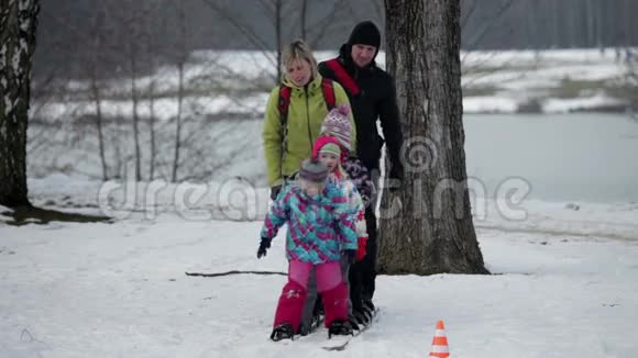 一家人在孩子摔倒的时候试图穿着大型滑雪板视频的预览图