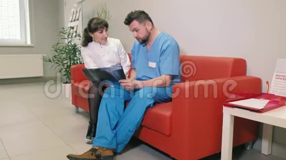 两个医生一男一女正坐在诊所的沙发上交谈4k视频的预览图