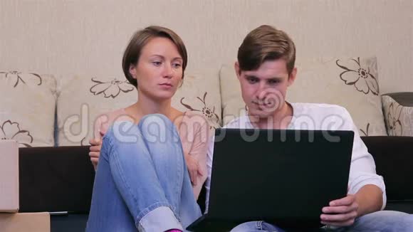 一对年轻夫妇带着笔记本电脑在地板上视频的预览图