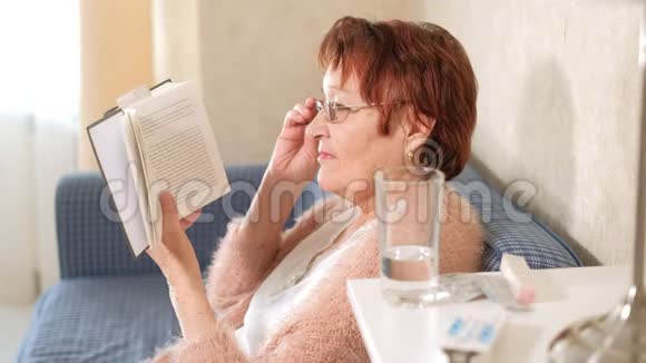 老太太在家里的沙发上看书视频的预览图