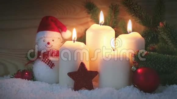 四支燃烧的圣诞蜡烛和带红色圣诞装饰的雪人视频的预览图