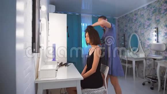 时尚的专业人士你可以信任美发师用吹风机给客户做头发背景是视频的预览图