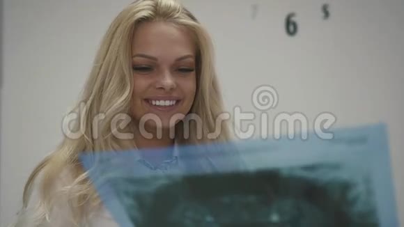 美丽的金发女孩听牙医与她交谈拿着X光片图像显示牙齿问题视频的预览图