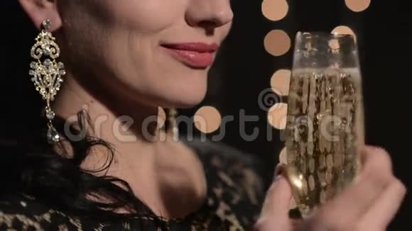 一个女人晚上在庆祝灯光的背景下喝着香槟视频的预览图