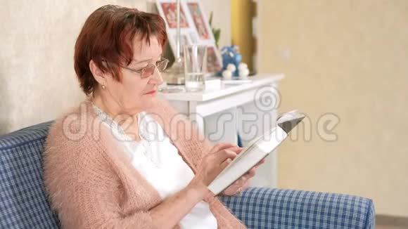 老太太在家里的沙发上看书视频的预览图