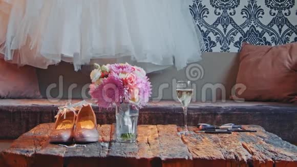 婚纱挂在墙上花束和鞋子在桌子上视频的预览图