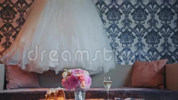 婚纱挂在墙上花束和鞋子在桌子上视频的预览图