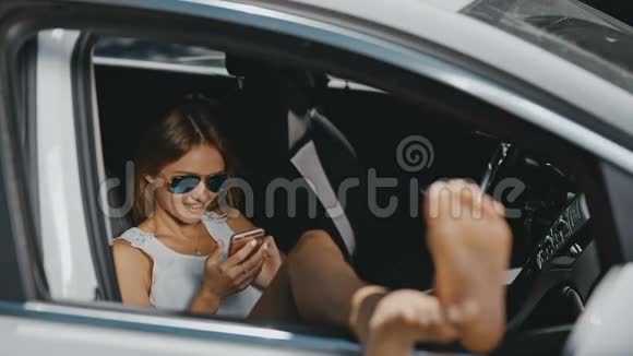 戴墨镜的年轻女子在车里休息送信视频的预览图