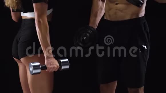 运动的男人和女人用哑铃弯曲他们的手在工作室的黑色背景上训练他们的二头肌视频的预览图