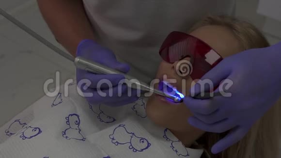 正在治疗的牙医病人口腔医生助理使用初级蓝光硬化牙科复合材料视频的预览图