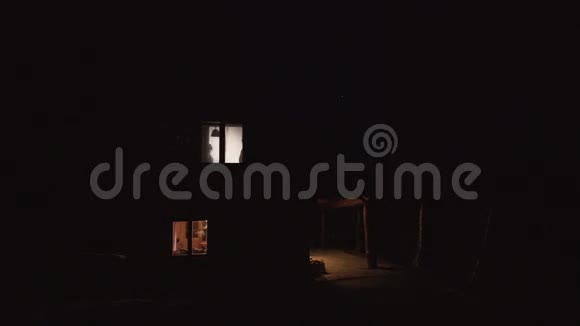 房子窗户后面那对接吻的夫妇的剪影被放置在黑暗的山上视频的预览图