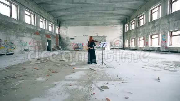 一个女人正在一座搁浅的大楼里拉小提琴视频的预览图