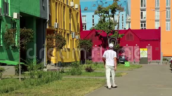 穿白衣服的人走在街上有许多彩色的建筑物视频的预览图
