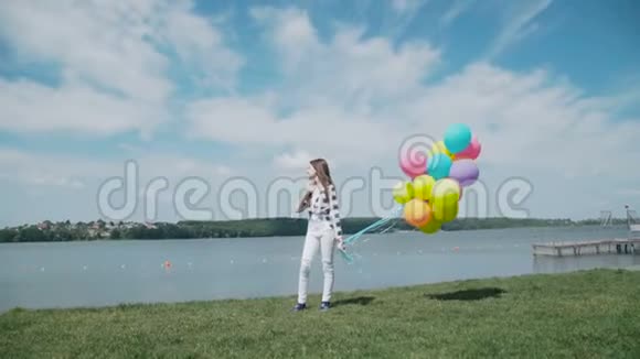 快乐的小女孩在夏天的海湾上摆着五颜六色的球视频的预览图