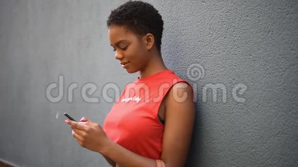 年轻的黑人妇女在城市背景下用她的智能手机发短信视频的预览图