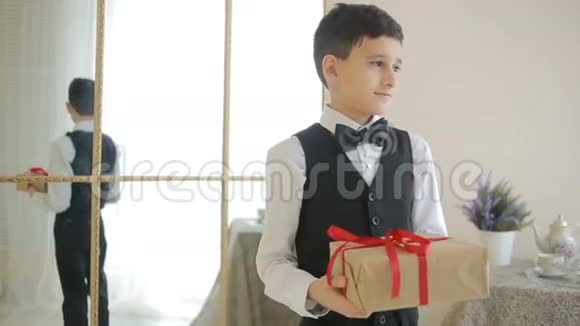 戴领结的快乐男孩拿着礼物视频的预览图