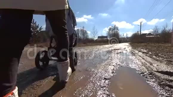 女孩在泥泞的乡间小路上推着婴儿车散步高清视频视频的预览图