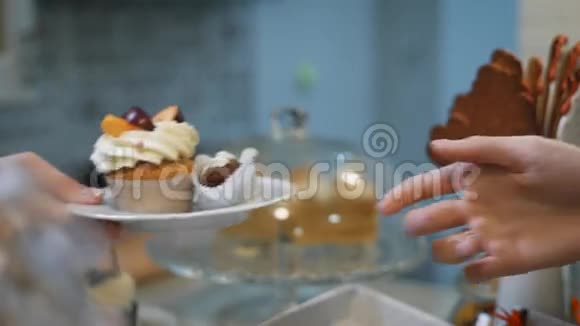 彩色指甲的糕点女孩送一只白色的小手一个盘子上面有两个美味的蛋糕一个是棕色的视频的预览图