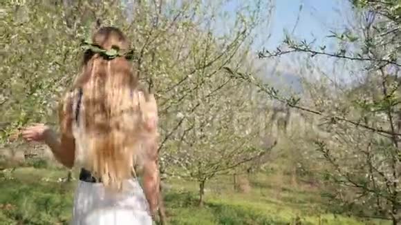 穿着长裙走在春花园里的年轻美女视频的预览图