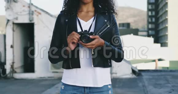 城市屋顶上拿着照相机的时髦年轻女子视频的预览图