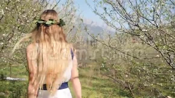 穿着长裙走在春花园里的年轻美女视频的预览图