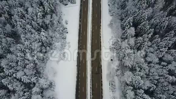 4K在冰冻的冬季森林里驾驶汽车飞越公路空中全景消失的角度视频的预览图
