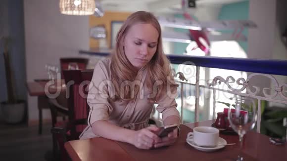 女人坐在餐厅里看着智能手机视频的预览图