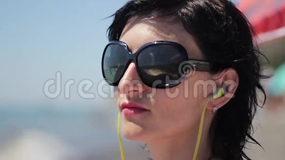 在海底背景下带上耳机和太阳镜听音乐的美丽年轻女子特写肖像视频的预览图
