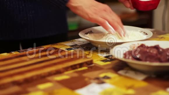 一个女人在厨房里用面粉蘸一块肝脏视频的预览图