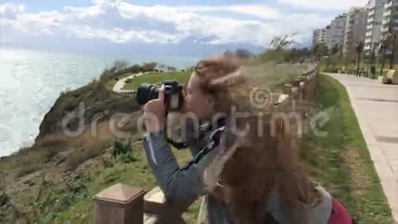 一位游客在安塔利亚拍摄地平线照片女孩摄影师用单反相机拍摄照片视频的预览图