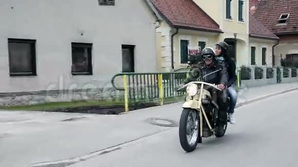 一对夫妇骑着复古摩托车穿过小镇视频的预览图