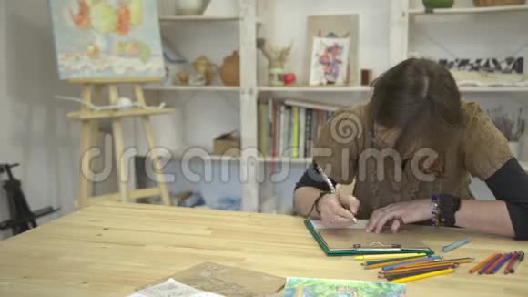 女人拿着彩色铅笔坐在书桌前画着图画或卡片视频的预览图