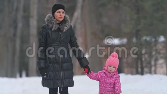 妈妈和她可爱的小女儿在冬天的公园散步视频的预览图