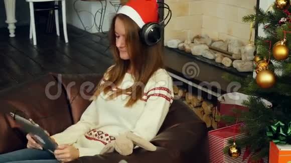 穿着红色圣诞帽和袜子的漂亮女孩用垫垫在圣诞树上视频的预览图